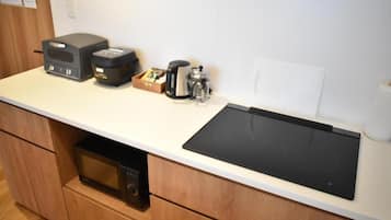 Une cuisine équipée d’un four à micro-ondes, d’une machine à café et d’une plaque de cuisson à induction noire.