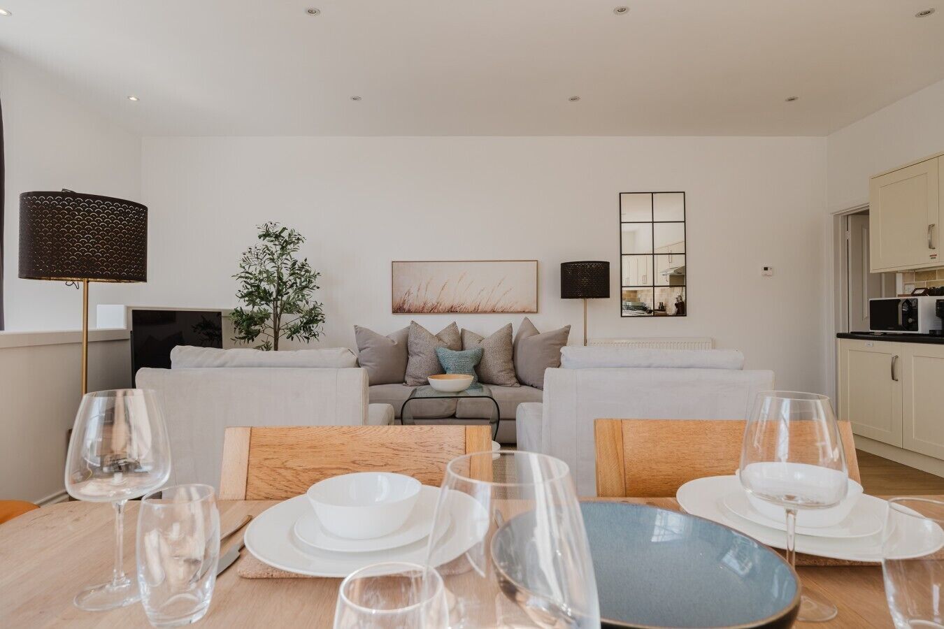 Een moderne woonkamer met een eethoek, een zithoek, een salontafel en een keuken op de achtergrond.