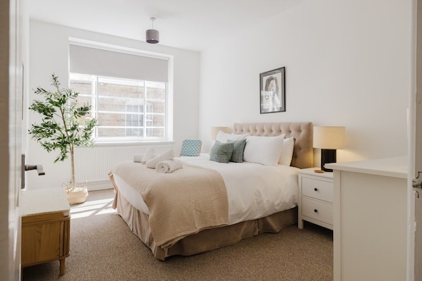 A bedroom with a bed, bedside tables, a lamp, a potted plant, and a window. - Stunning Loft Apartment With Private Parking (Chipping Norton)