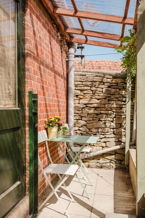 A patio area with a brick wall, a stone wall, a pergola, and a table with chairs.