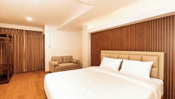 Une chambre d’hôtel moderne dotée d’un grand lit, d’un coin salon et d’un mur revêtu de panneaux en bois.