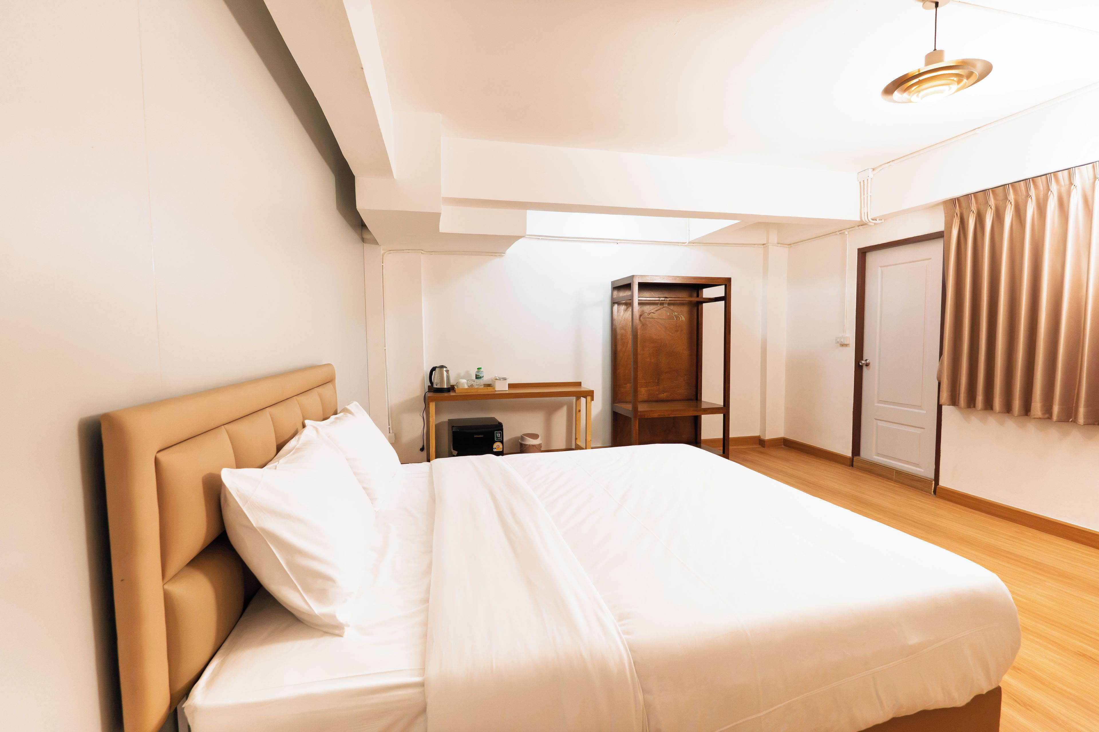 A hotel room with a bed, a desk, a wardrobe, and a door.