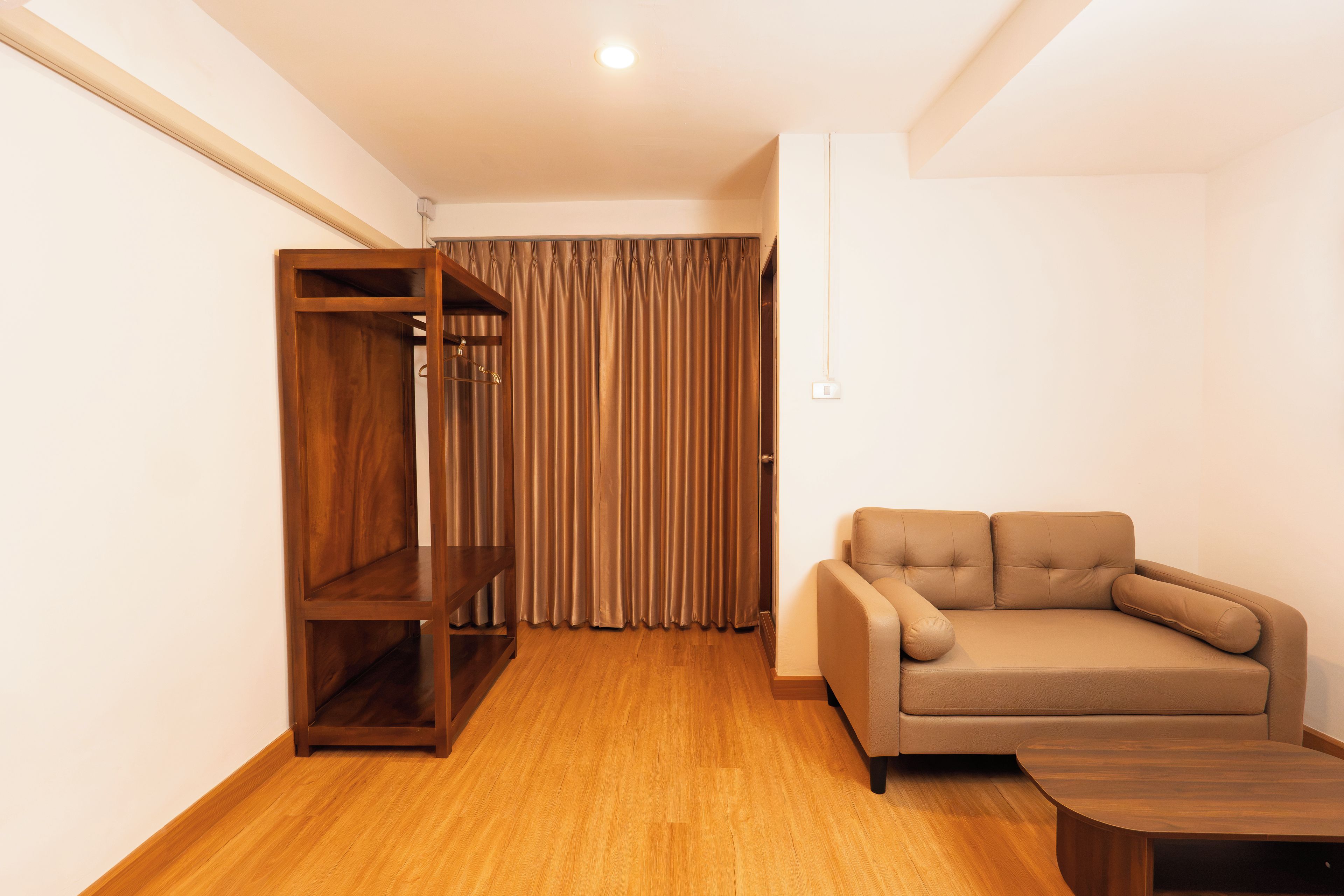 A room with a wooden wardrobe, a beige sofa, and a wooden coffee table.