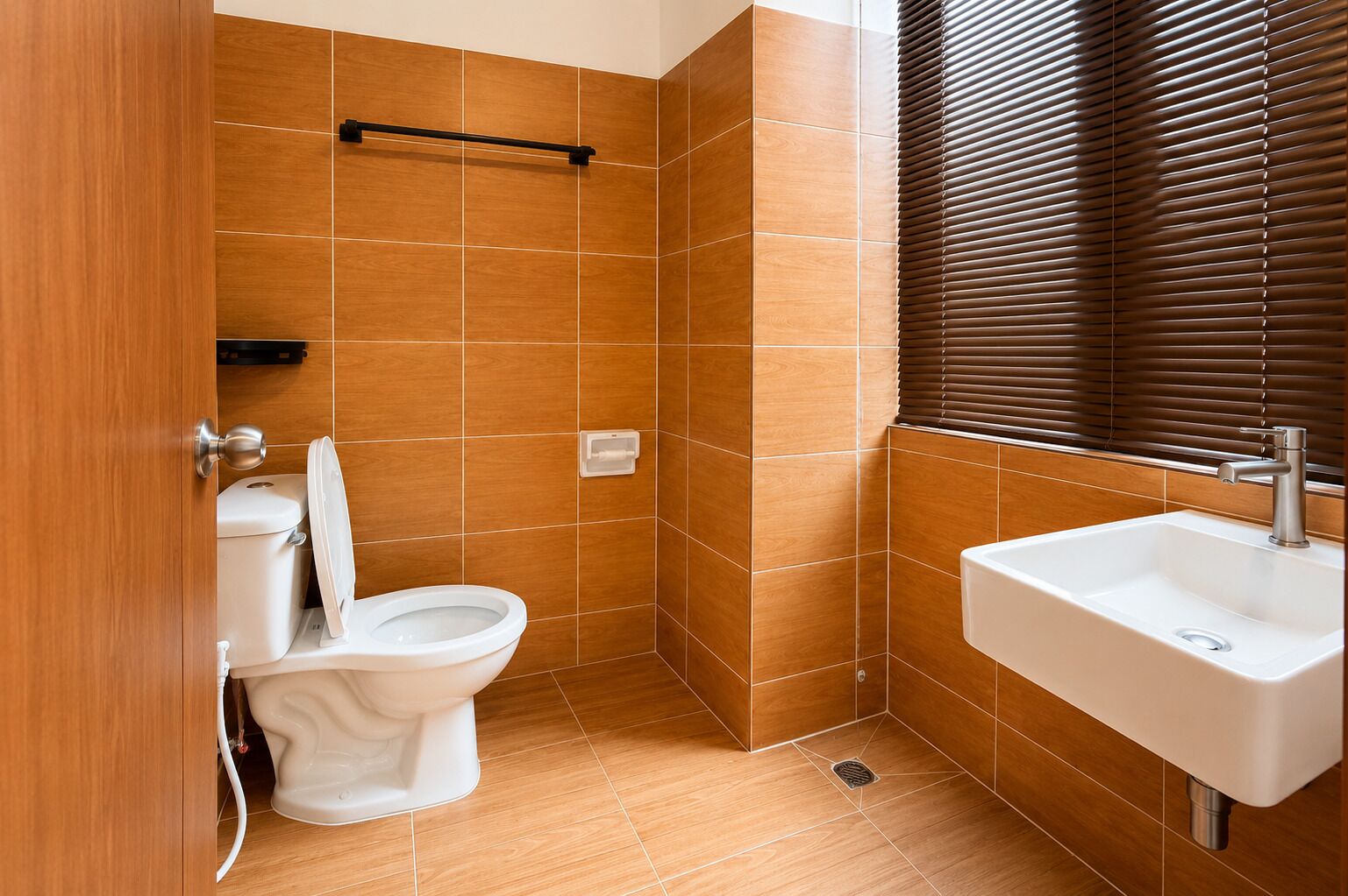 Un baño con inodoro, lavamanos y baldosas de madera.