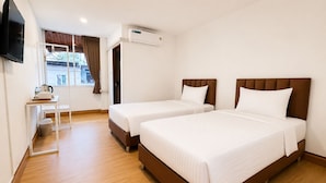 Quarto de hotel com duas camas, uma escrivaninha, uma televisão e ar condicionado.