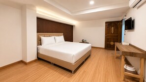 A bedroom with a bed, bedside table, and a wooden desk. - Three One Hotel (Bangkok)