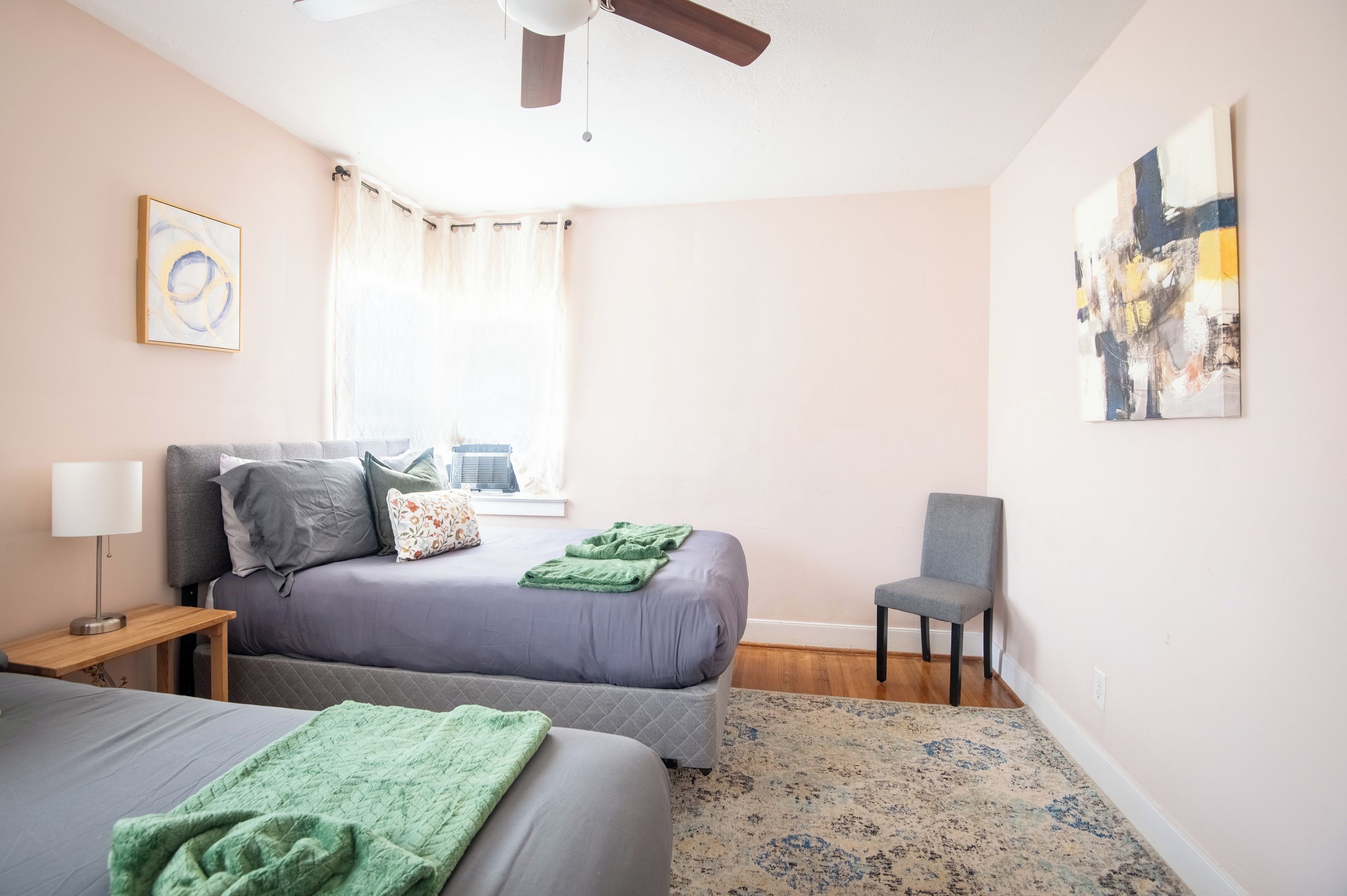 Un dormitorio con cama, una silla, una lámpara y un ventilador de techo.