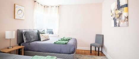 Une chambre à coucher avec un lit, une chaise, une lampe et un ventilateur de plafond.