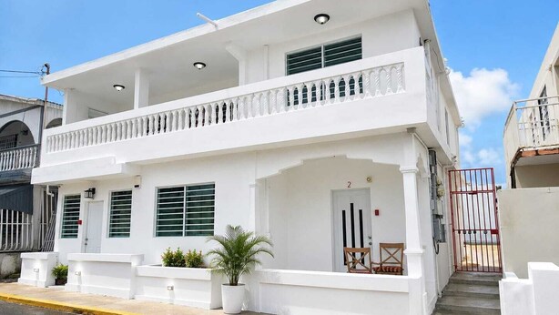 Un bâtiment à deux étages doté d’un balcon, d’une porte et d’un portail.