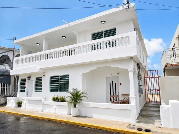 A two-story building with a balcony, a door, and a gate.