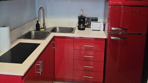 Une cuisine rouge équipée d’un four à micro-ondes, d’un évier, d’une cuisinière et d’un réfrigérateur de la marque Galanz.