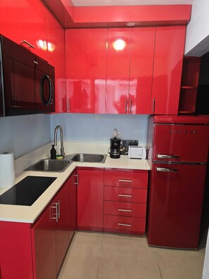 A red kitchen with a microwave, sink, stove, and a Galanz refrigerator.