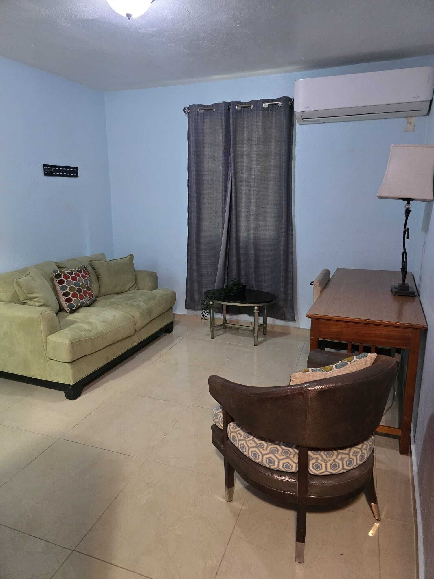 A living room with a sofa, a chair, a small table, and a lamp.