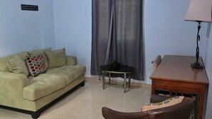 Un salon avec un canapé, un fauteuil, une petite table et une lampe.