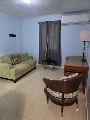A living room with a sofa, a chair, a small table, and a lamp.