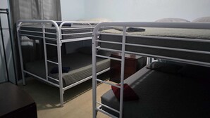 Une chambre de dortoir avec des lits superposés, un rideau et une vue sur l’extérieur.
