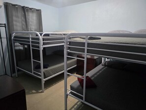 A dormitory room with bunk beds, a curtain, and a view of the outdoors.