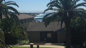 A building with a tiled roof, surrounded by palm trees, overlooking a body of water.