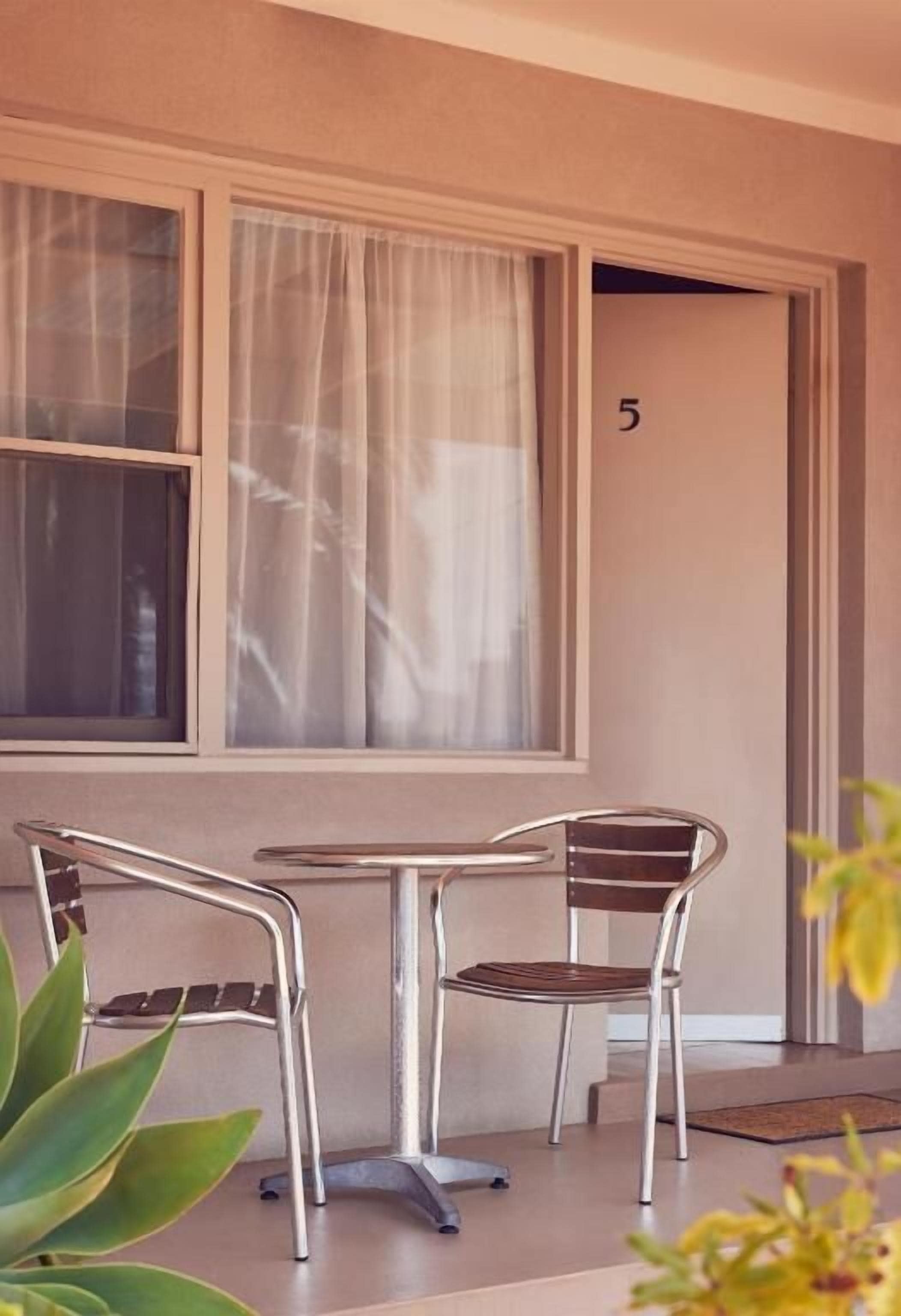 A room with a window, a door marked with the number 5, and a small table with two chairs.