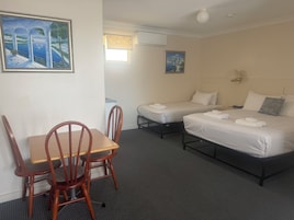 Habitación de hotel con cama, escritorio y silla. Hay dos camas, una más grande y otra más pequeña.