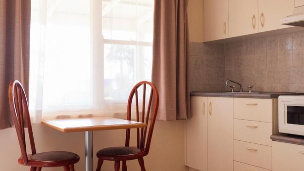 Una cocina con ventana, una mesa, dos sillas y un microondas.