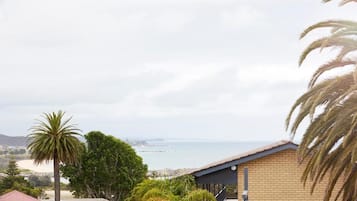 A coastal property with a view of the sea, a brick building, and a palm tree.