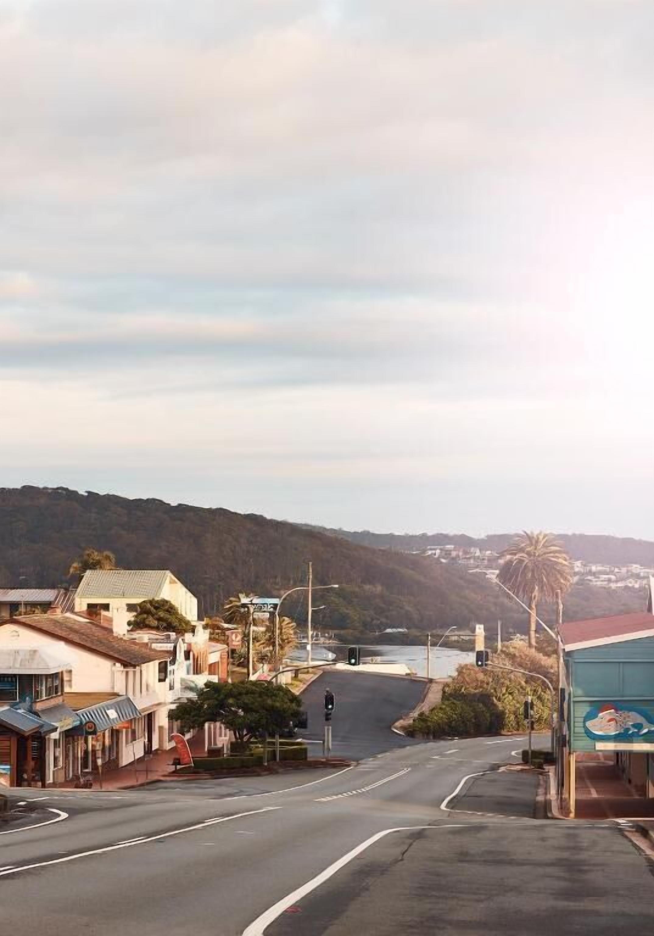 A coastal street with buildings, a clear sky, and a view of the sea.