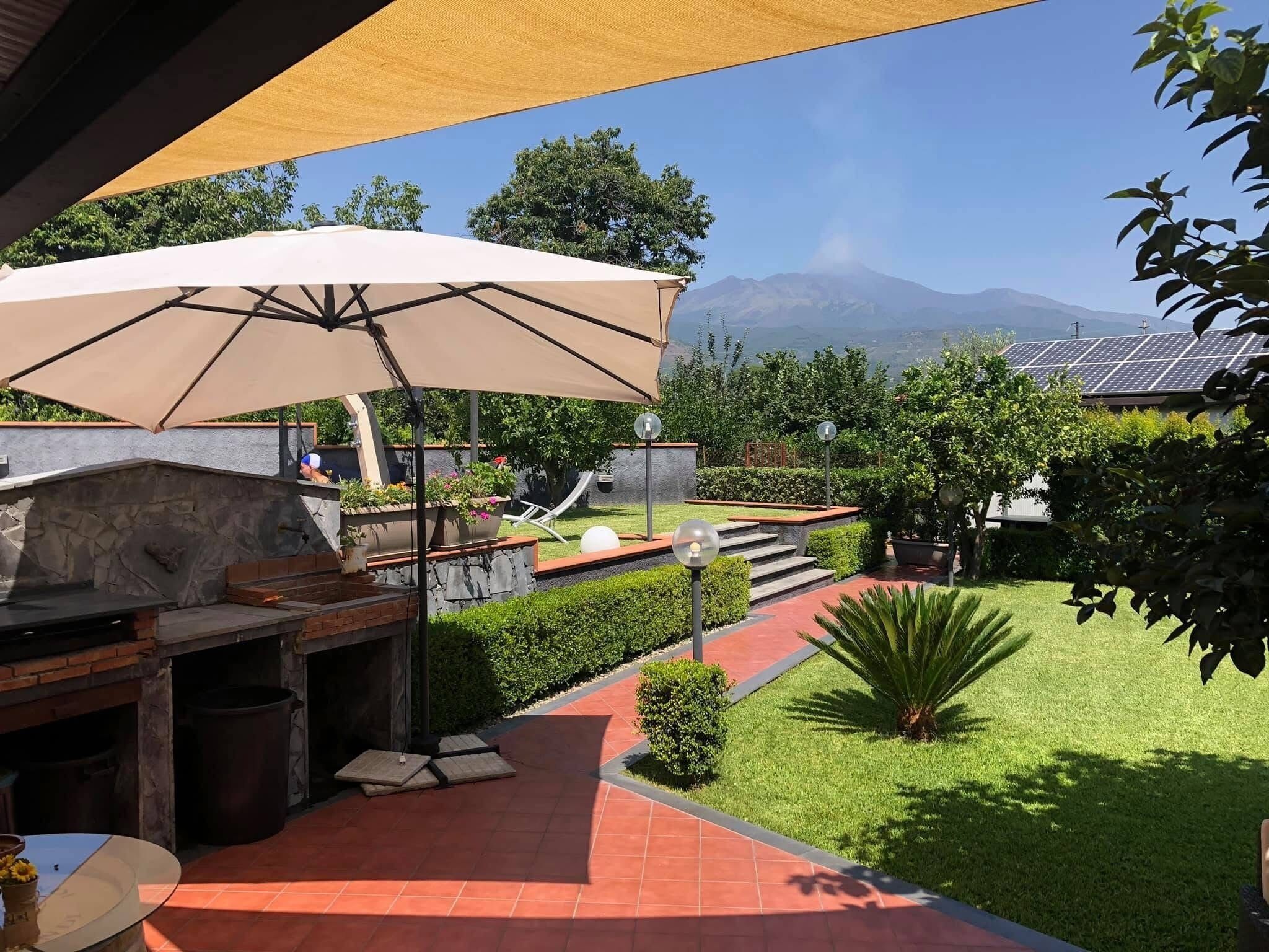 A patio with a barbecue grill, outdoor seating, and a view of mountains.