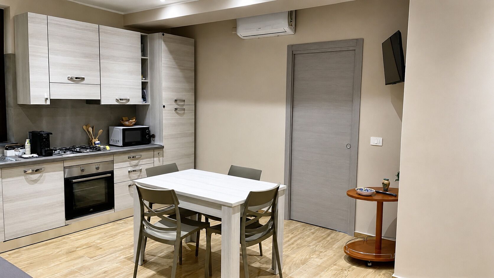 Une cuisine compacte avec un coin repas, comprenant des placards, un four à micro-ondes, une cuisinière et une table avec des chaises.