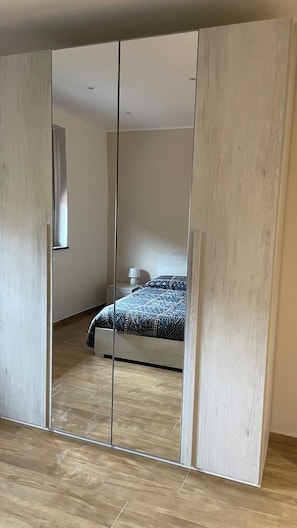 A bedroom with a bed, a nightstand, and a mirror. - Cozy apartment with a view of Mount Etna, a spacious garden, and a relaxing atmosphere. No pets. (Aci Sant’Antonio)
