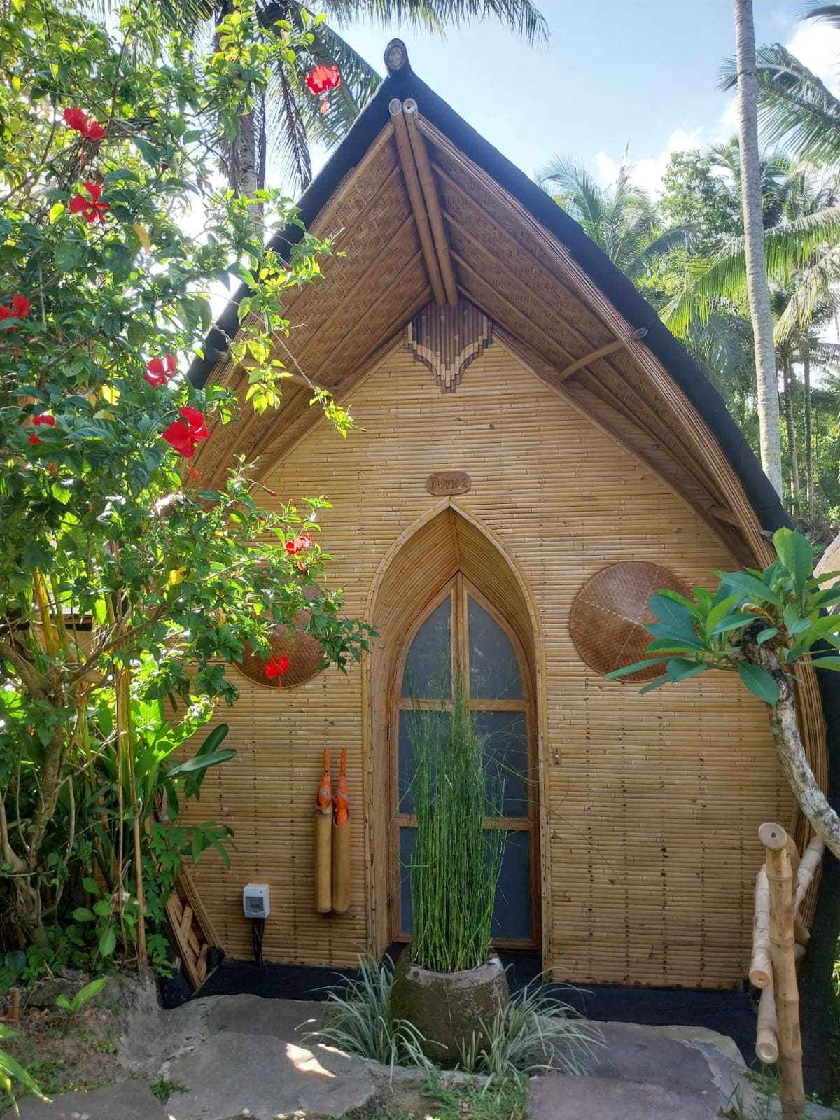 A traditional wooden building with a thatched roof, a central arched doorway, and a small window.