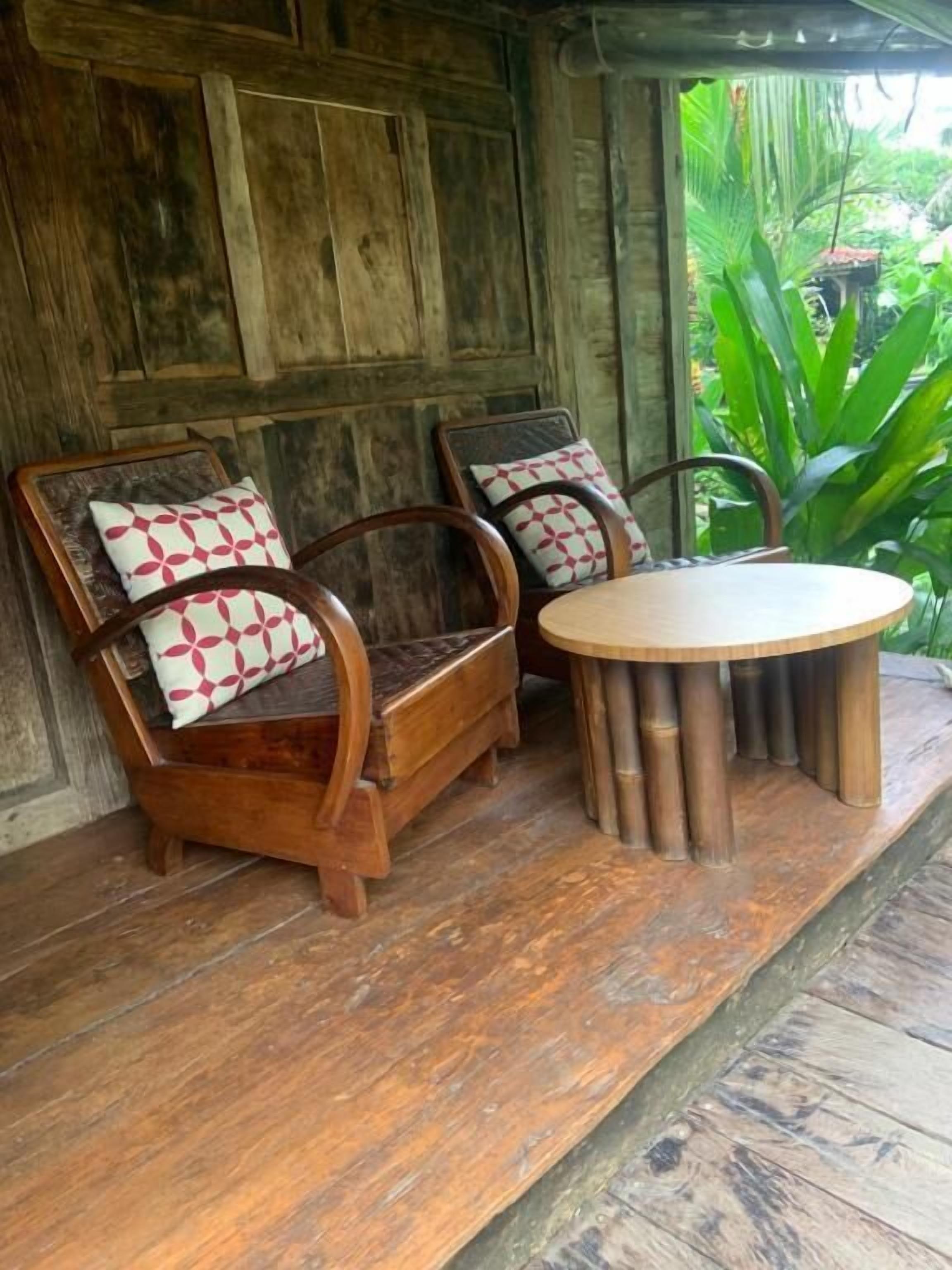 A wooden porch with two wooden chairs and a round table.