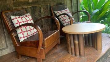 A wooden porch with two wooden chairs and a round table.