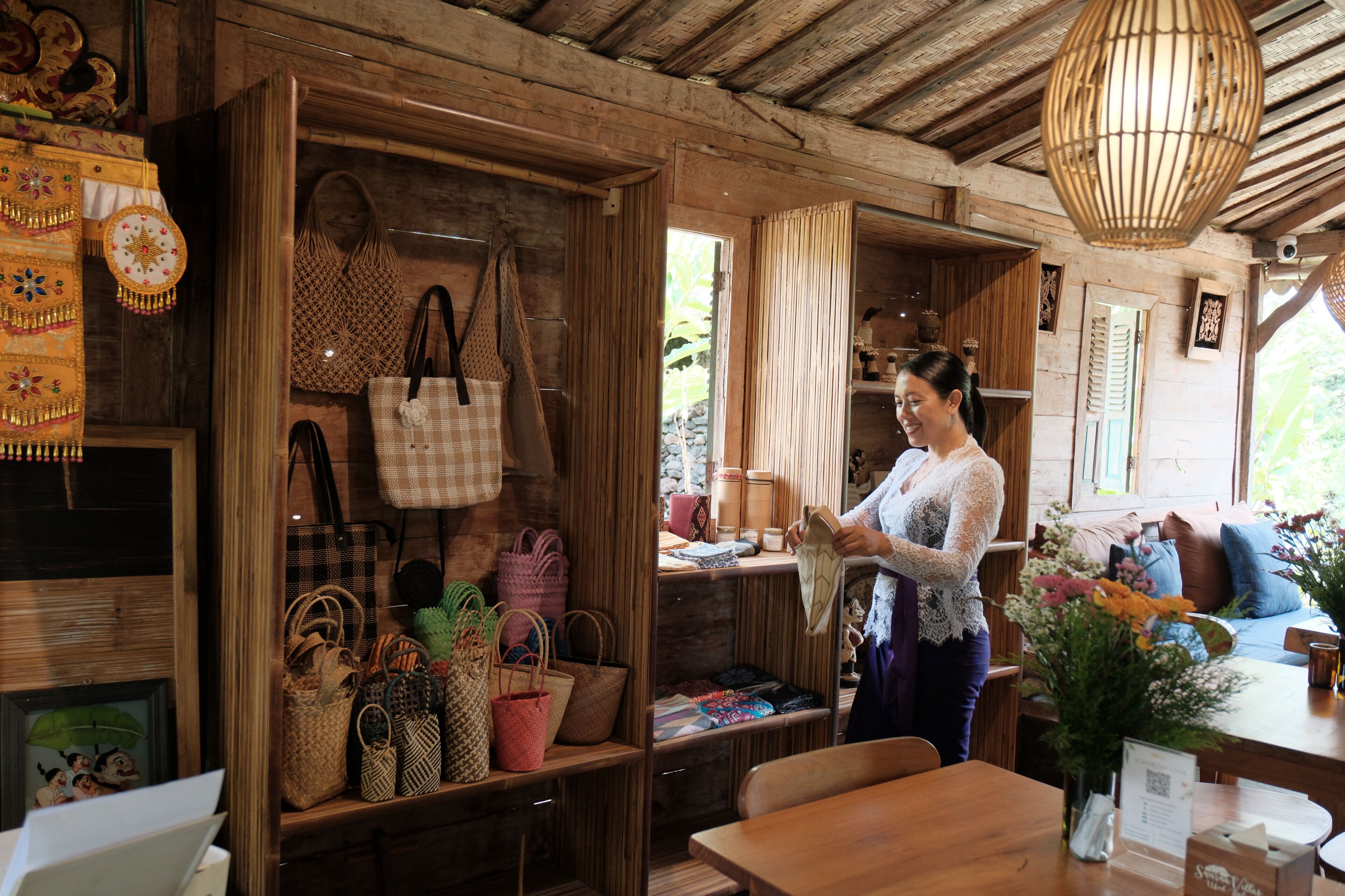 Interior de madera con exhibición de bolsas tejidas y una persona sosteniendo una bolsa.