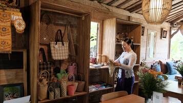 Interior de madera con exhibición de bolsas tejidas y una persona sosteniendo una bolsa.