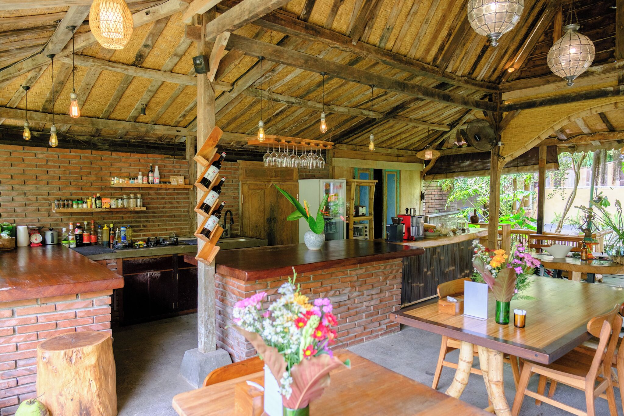 A rustic bar area with wooden beams, a brick counter, and a variety of bottles and glasses.