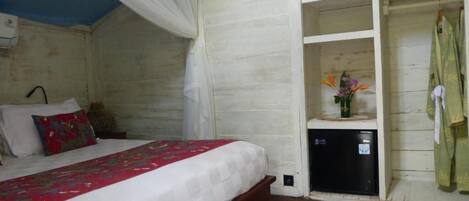 A bedroom with a bed, a bedside table, a nightstand, a wardrobe, and a small shelf with decorative items.