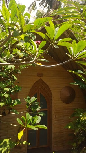 Una estructura de madera con un arco apuntado y abundante follaje verde.