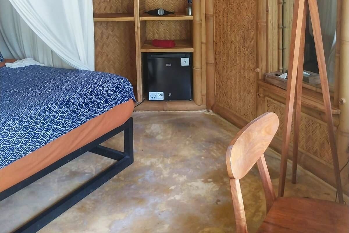 Una habitación con cama, silla, estantería y lámpara.