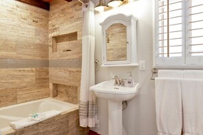 A bathroom with a bathtub, a sink with a mirror above it, and a window with blinds. - Moon Palace 2170 (Big Bear City)