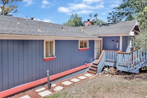 A house with a dark blue exterior, a red front door, and a wooden staircase leading to a porch.