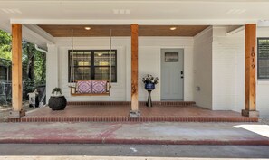 A porch with a swing, a door, and a potted plant. - Harrington: 1 Min From Main Entrance to Texas A&M (College Station)