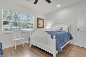 A bedroom with a white bed, a bench, a window with blinds, a framed picture, and a door. - Harrington: 1 Min From Main Entrance to Texas A&M (College Station)