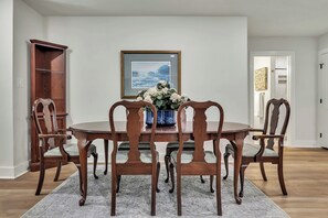 A dining room with a round wooden table, six chairs, a vase with flowers, a framed picture on the wall, and a wooden cabinet. - Harrington: 1 Min From Main Entrance to Texas A&M (College Station)