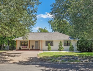 A single-story house with a front porch, a small garden, and a clear blue sky. - Harrington: 1 Min From Main Entrance to Texas A&M (College Station)