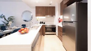 Cuina moderna amb una illa central, electrodomèstics d'acer inoxidable i armaris de fusta.
