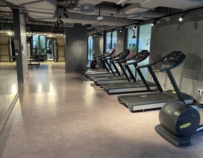 Ein Fitnessraum mit Laufbändern an einer Wand, einem Rudergerät und Trainingsgeräten im Hintergrund.