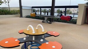 Un parque infantil con una mesa giratoria central y asientos circundantes naranja y negro.