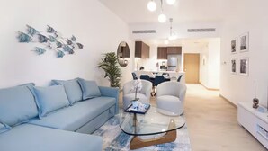 Una sala de estar moderna con un sofá, una mesa de centro de vidrio y una zona de comedor con sillas.