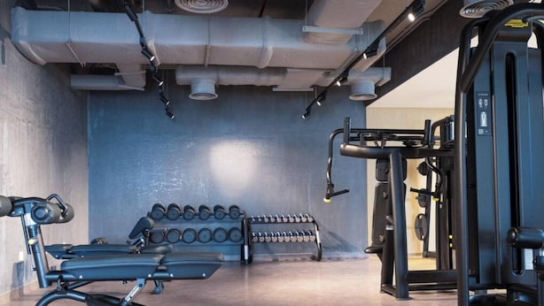 Un gimnasio con equipamiento de ejercicio, incluyendo una banca, mancuernas y una estructura para sentadillas.